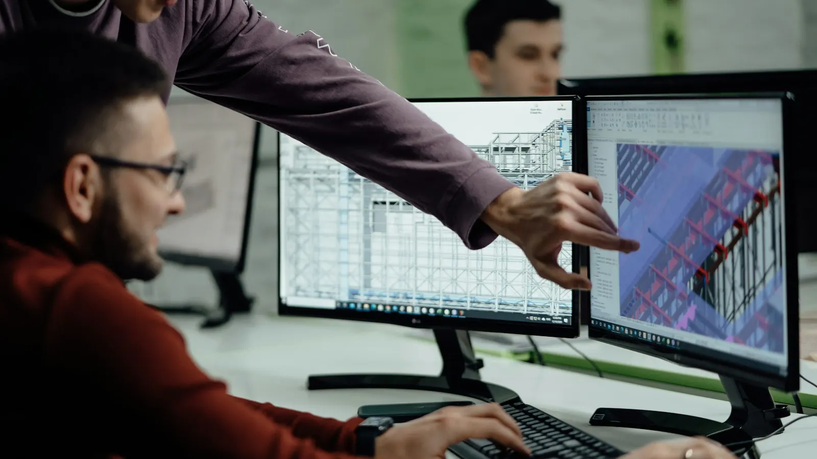 Dos técnicos revisan un modelo BIM de un edificio en dos monitores